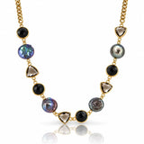 A gold chain necklace featuring alternating round black onyx beads, faceted smoky quartz triangle beads, and irregular iridescent pearl beads in gold settings, displayed on a clean white background with a soft reflection.