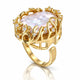 A gold ring featuring a large, oval iridescent pearl surrounded by delicate gold filigree and small clear accent stones, set against a clean white background with a soft reflection.