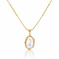 A gold necklace with a beaded chain and a bezel-set irregular baroque pearl pendant, shown on a clean white background with a soft reflection below.