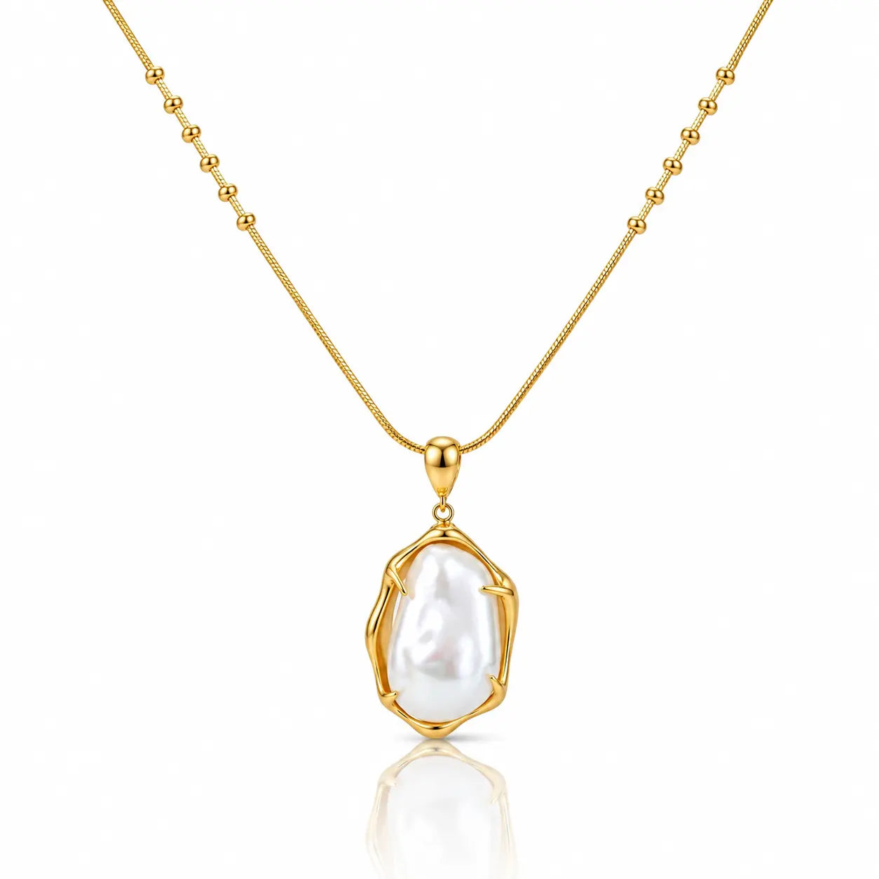 A gold necklace with a beaded chain and a bezel-set irregular baroque pearl pendant, shown on a clean white background with a soft reflection below.