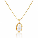 A gold necklace with a beaded chain and a bezel-set irregular baroque pearl pendant, shown on a clean white background with a soft reflection below.