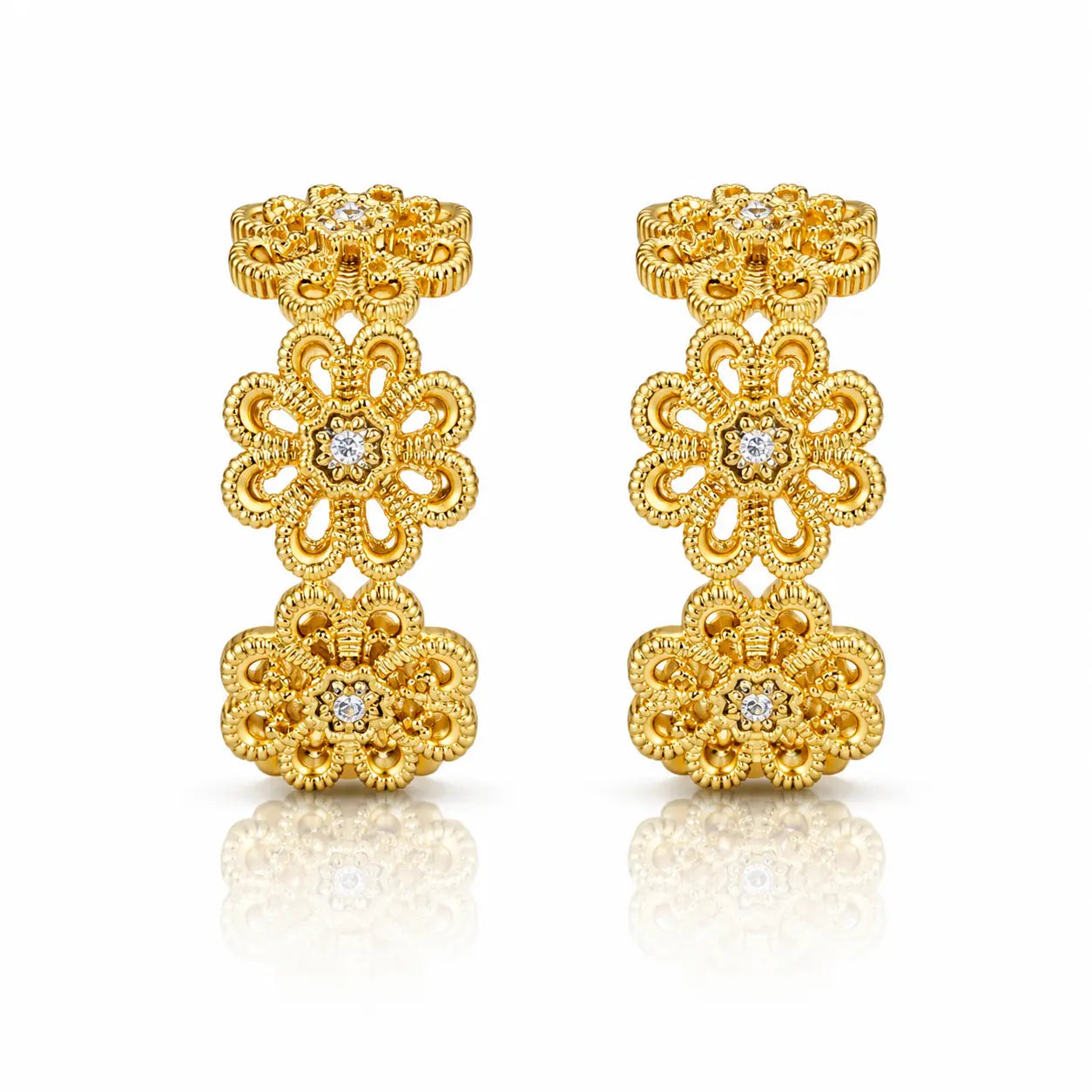 A pair of gold filigree earrings with floral motifs and small clear gemstones, displayed on a clean white background with a soft reflection below.