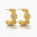 Gold filigree hoop earrings with floral design and small clear stones on white background