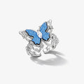 White gold plated silver ring with blue butterfly and clear gemstone center on white background