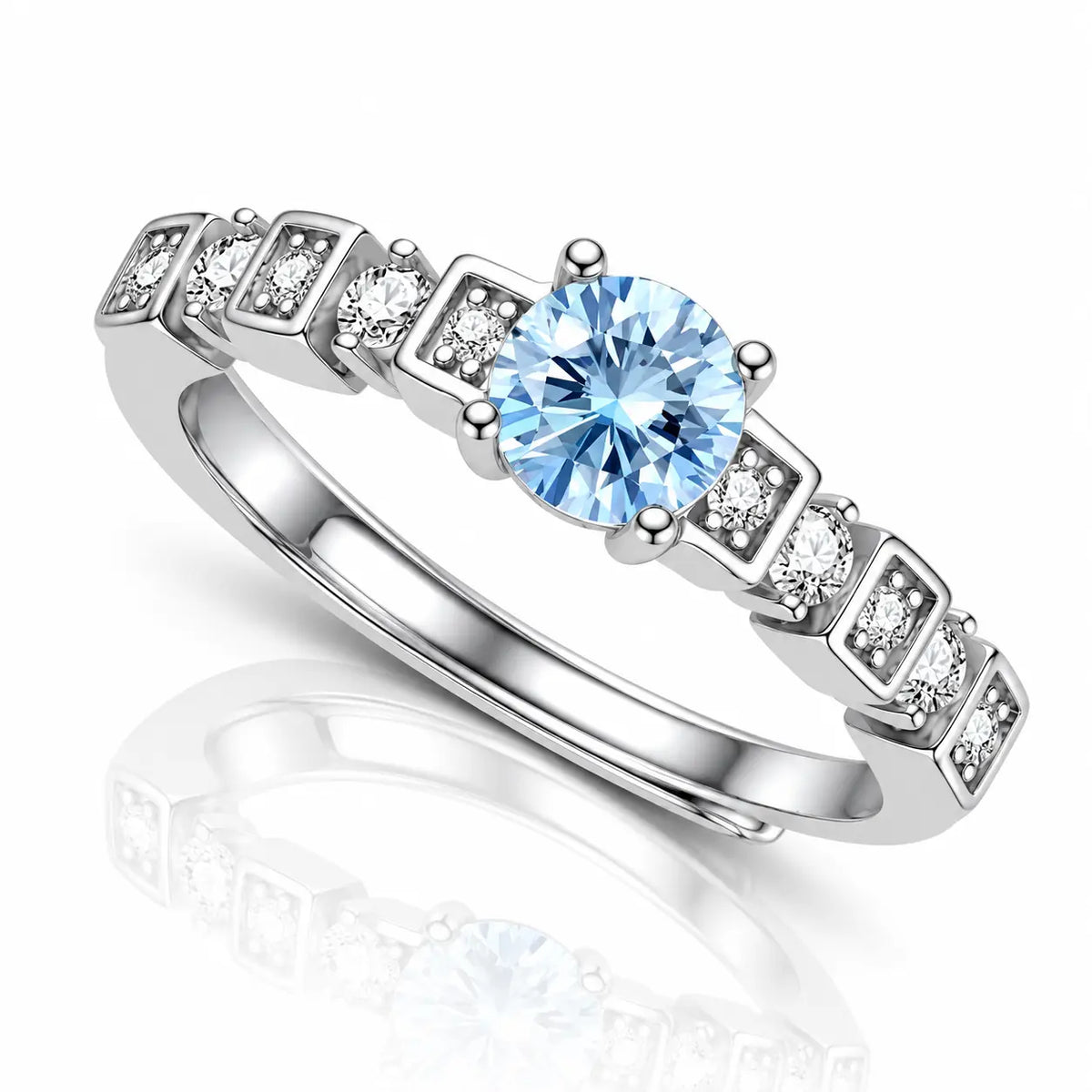 A silver-toned ring featuring a round light blue center stone and a row of square-cut clear accent stones on a white background with a soft reflection.