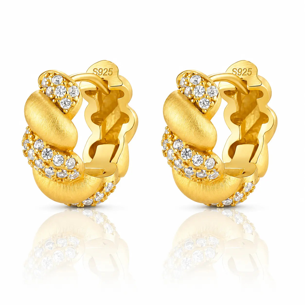 A pair of gold huggie hoop earrings with clear pavé-set round stones, shown on a white background with a soft reflection below. The inside of the earrings is stamped with 'S925' indicating sterling silver base metal.