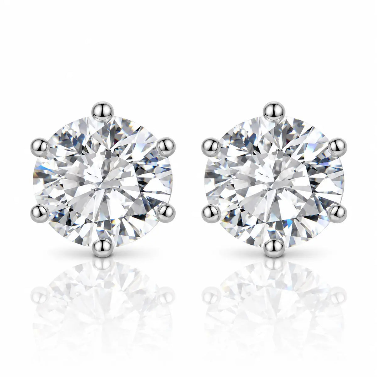 A pair of round-cut diamond stud earrings in a six-prong setting, shown on a clean white background with soft reflections below.