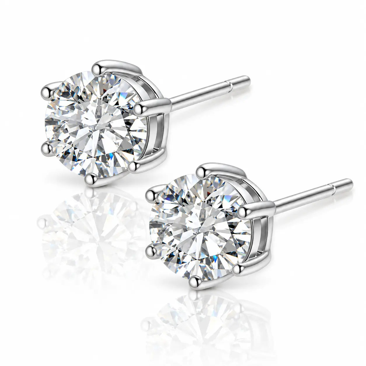 A pair of round-cut diamond stud earrings in a polished silver-tone setting, displayed on a clean white background with soft reflections below.