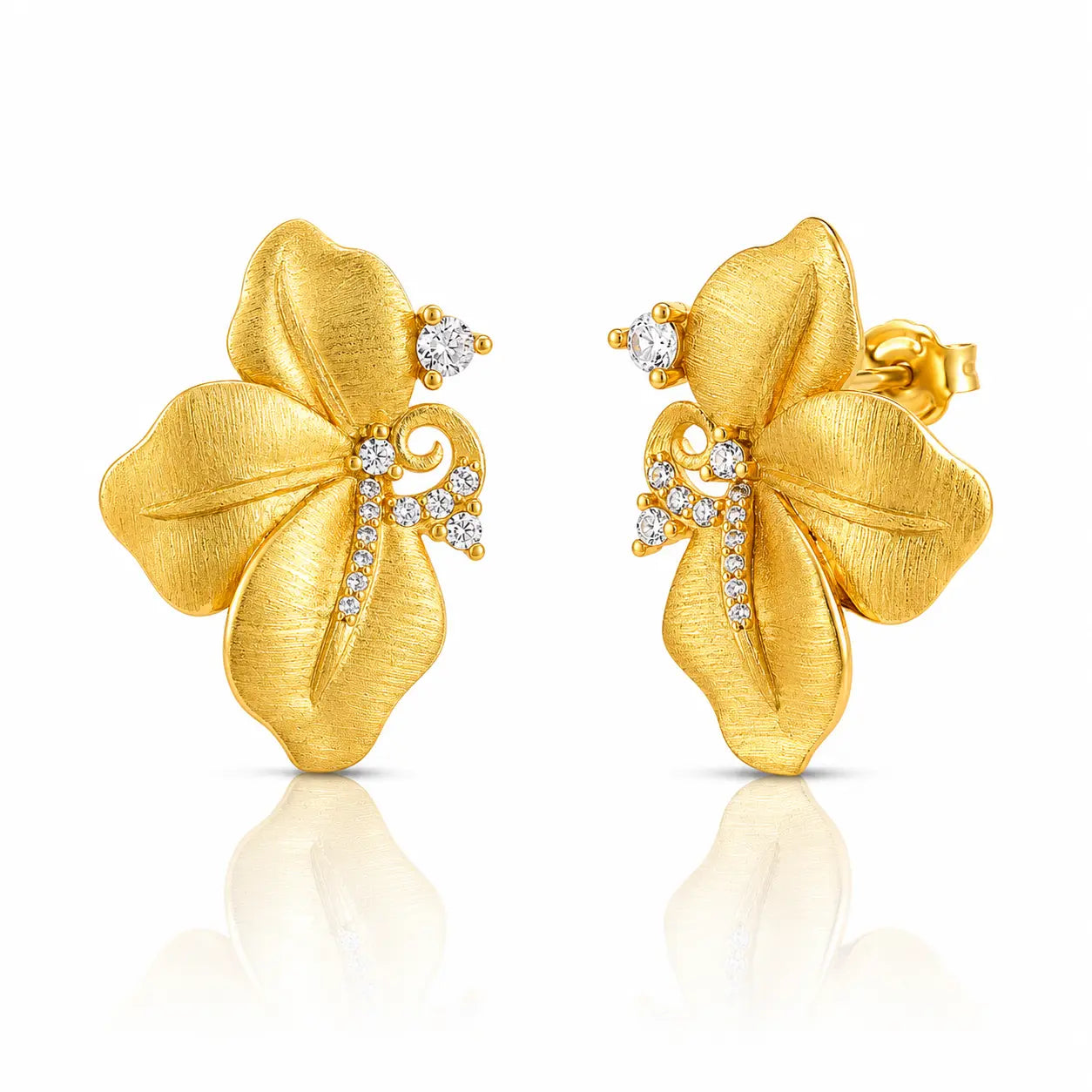 A pair of gold flower-shaped stud earrings with textured petals and small clear gemstone accents, shown on a white background with a soft reflection below.