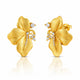 A pair of gold flower-shaped stud earrings with textured petals and small clear gemstone accents, shown on a white background with a soft reflection below.