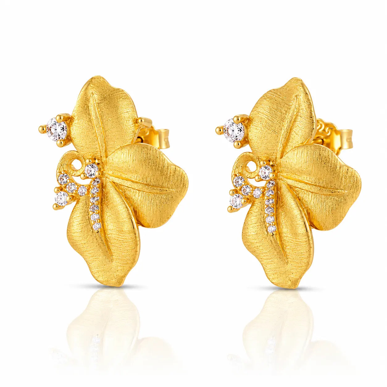 A pair of gold flower-shaped stud earrings with small clear gemstones, shown on a clean white background with a soft reflection below.