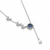 A silver Y-shaped necklace featuring three butterfly charms lined with small clear crystals, leading to a round bezel-set iridescent purple gemstone, shown on a white background.