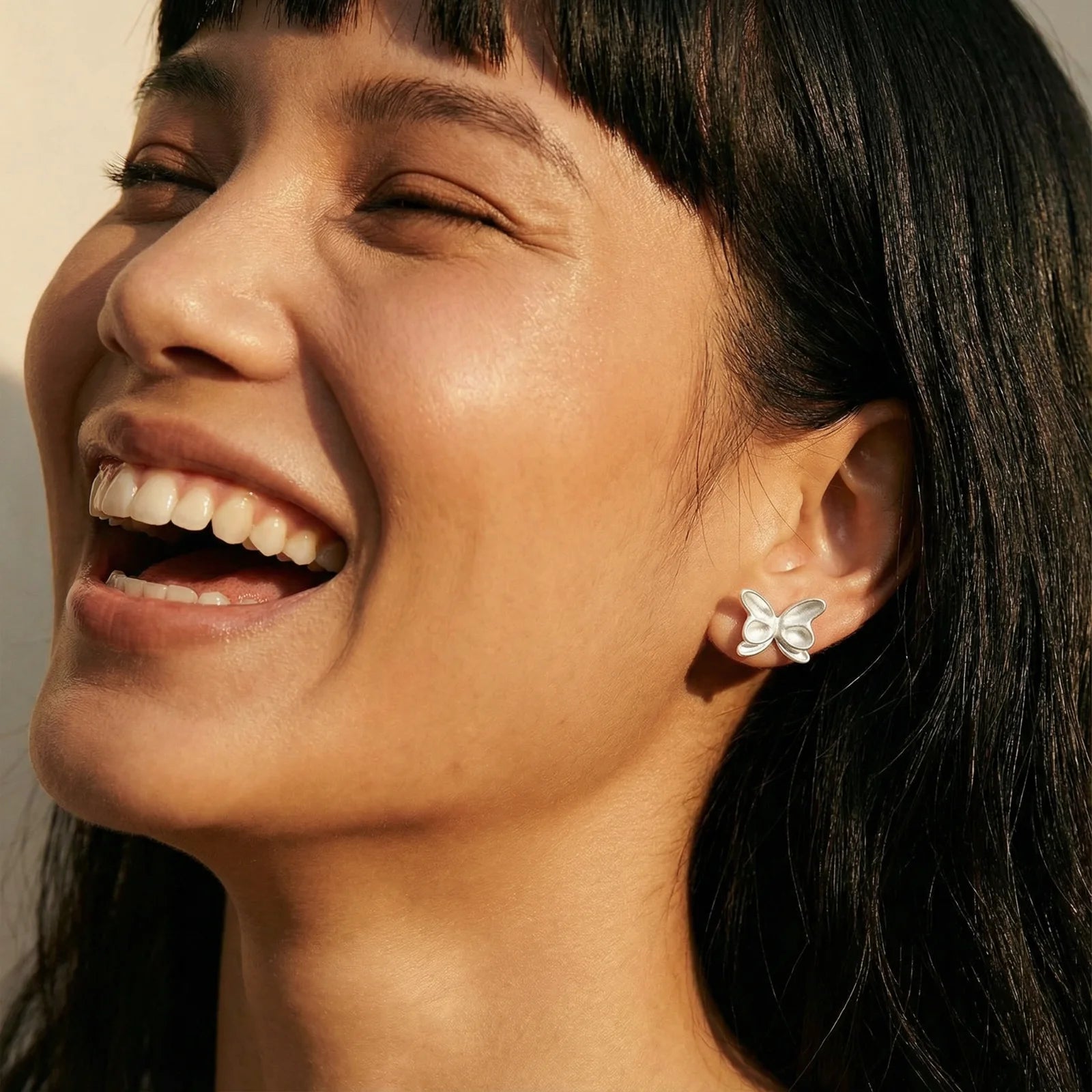 Woman wearing butterfly earrings with a neutral background