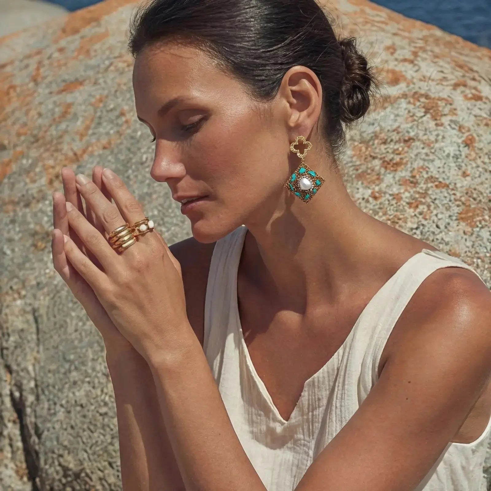 Woman wearing elegant earrings and rings against a natural background