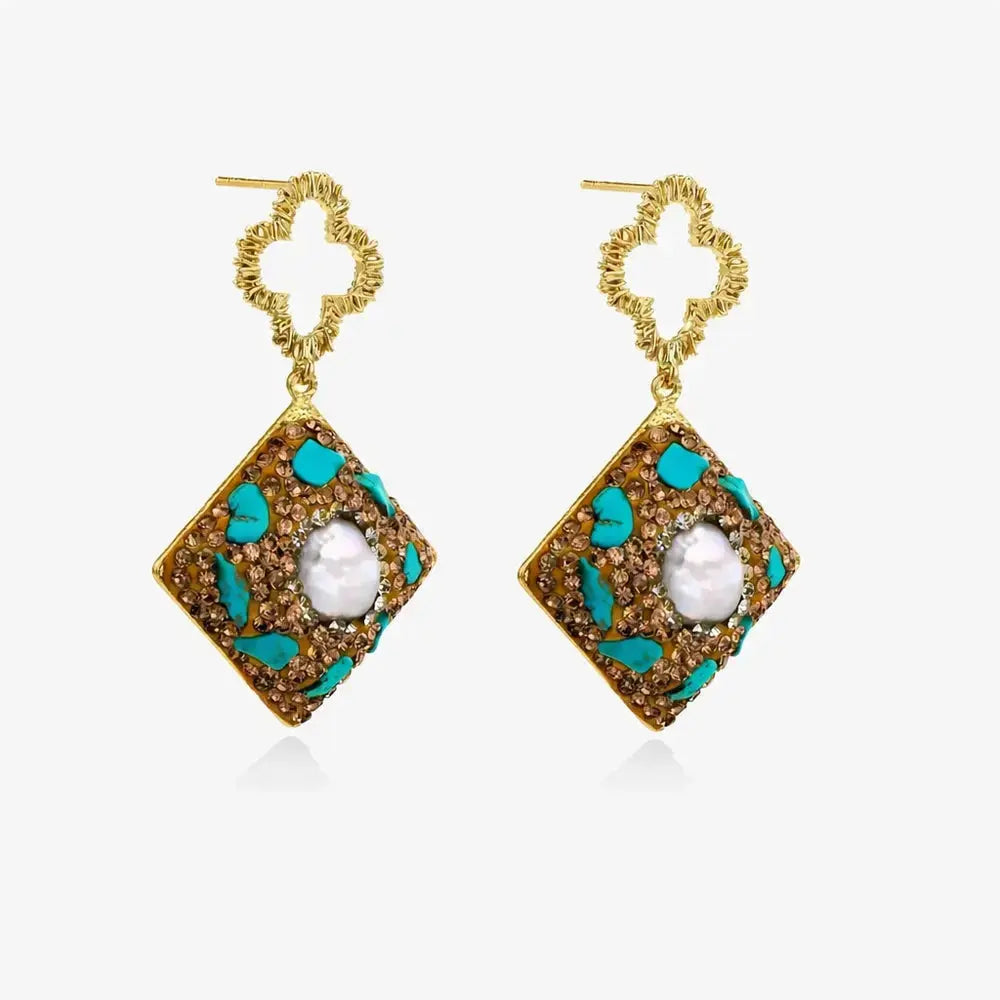 Pair of gold earrings with a diamond-shaped design and a central pearl on a white background
