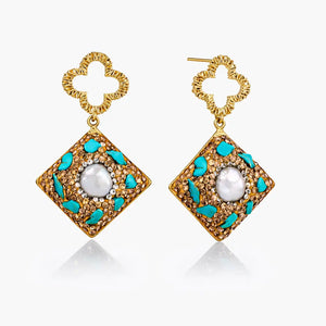 Pair of gold earrings with turquoise accents and a central pearl on a white background