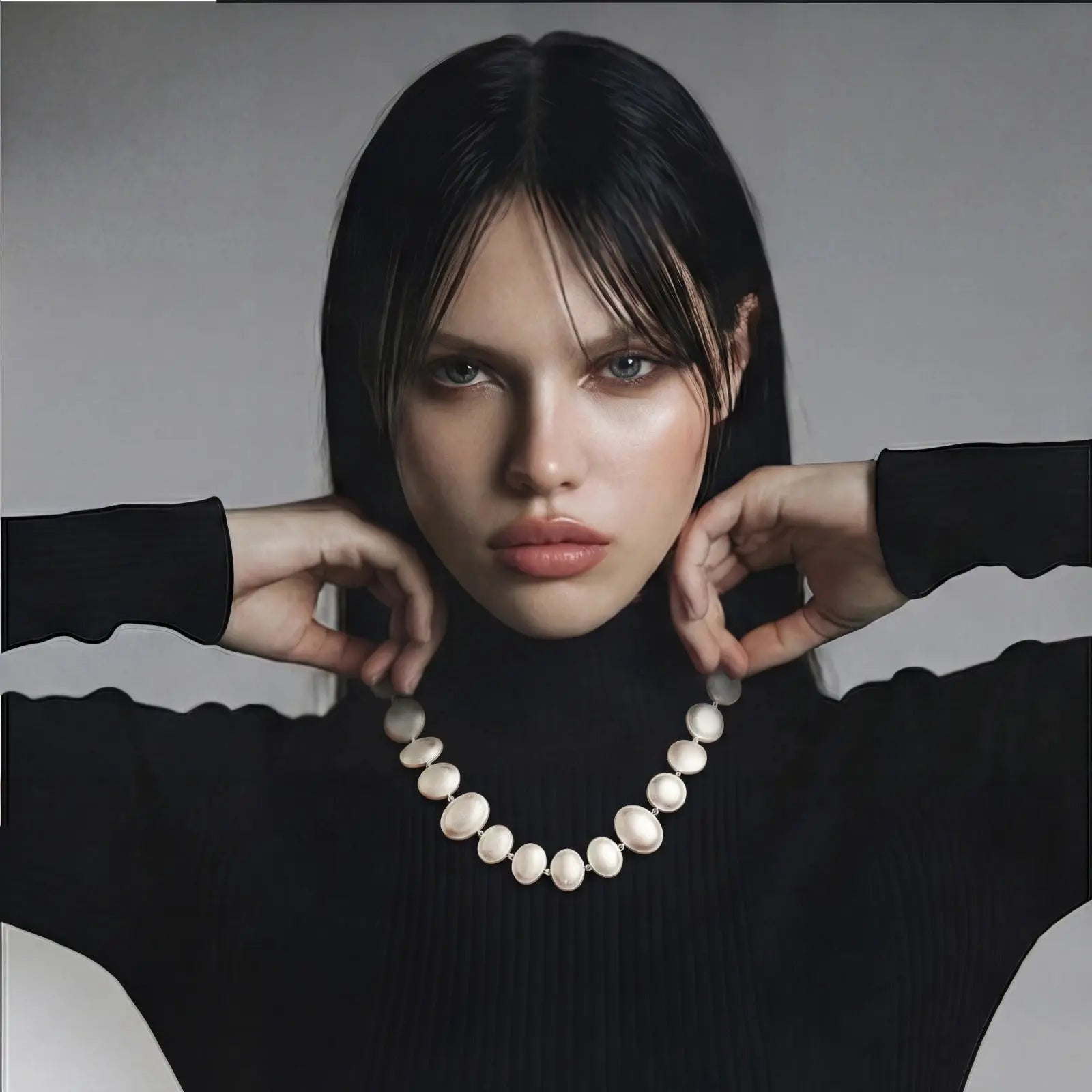 Woman holding a pearl necklace against a neutral background
