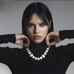 Woman holding a pearl necklace against a neutral background