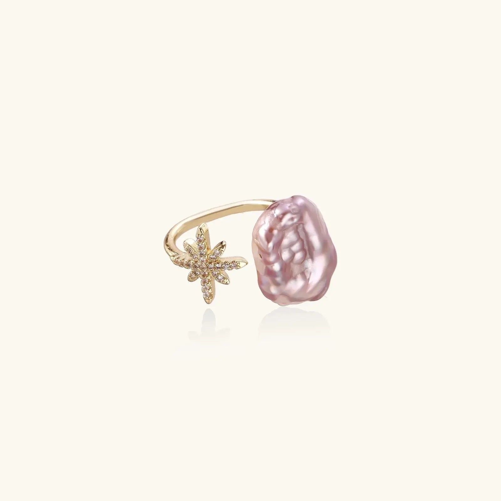 Gold ring with a pink pearl and starfish design on a white background