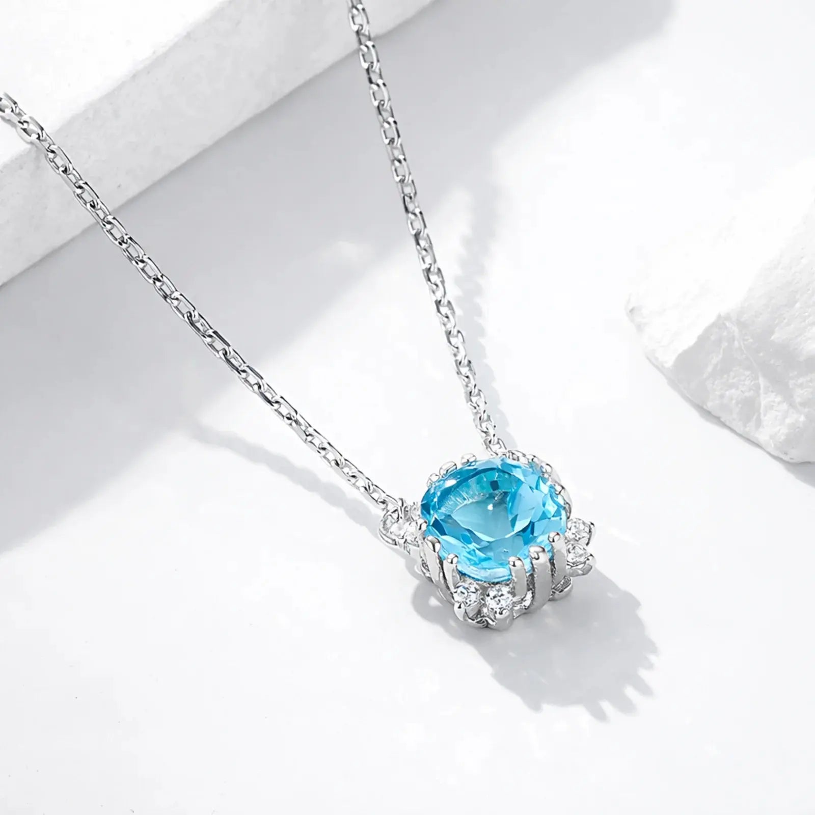 Silver gold plated necklace with oval blue topaz halo pendant on white background