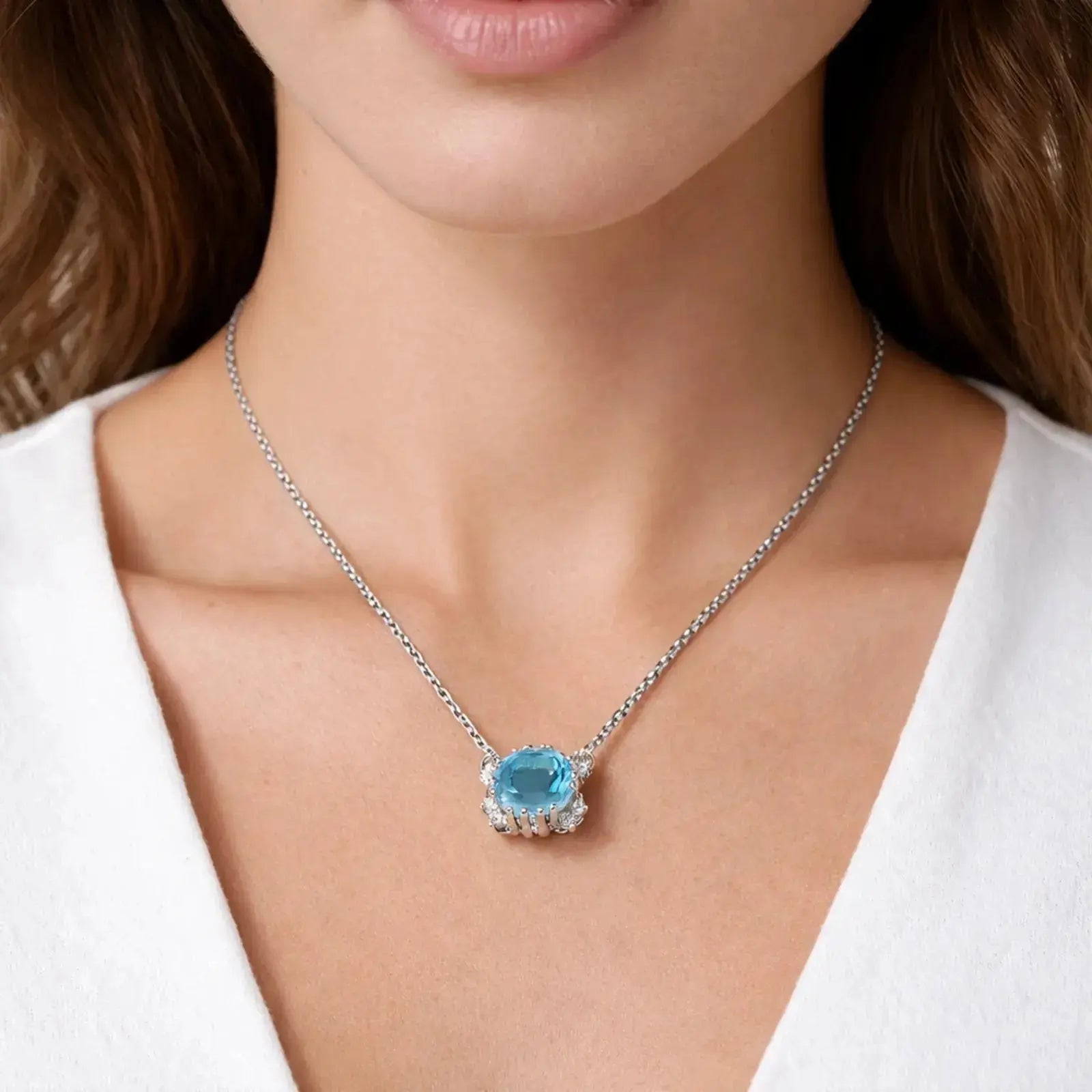 Woman wearing a silver necklace with a blue topaz halo pendant