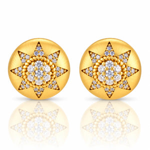 A pair of round gold starburst stud earrings set with clear gemstones, displayed on a clean white background with a soft reflection below.