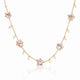 A delicate gold chain necklace featuring five pale pink star-shaped charms and small white pearl beads, displayed on a clean white background with a soft reflection.