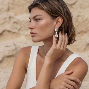 Woman wearing floral earrings against a natural background