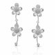 A pair of silver dangle earrings featuring textured five-petal flower charms with small clear stones in the centers, connected by curved stems with bead ends, shown on a white background with a soft reflection.