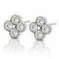 A pair of diamond stud earrings in a four-petal flower setting, crafted in silver-toned metal with a central pearl-like bead, shown on a reflective white surface.