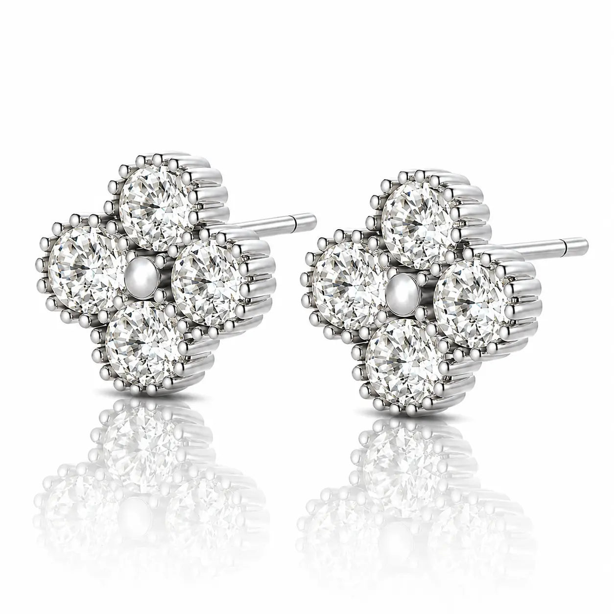 A pair of diamond stud earrings in a four-petal flower setting, crafted in silver-toned metal with a central pearl-like bead, shown on a reflective white surface.