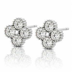 A pair of diamond stud earrings in a four-petal flower setting, crafted in silver-toned metal with a central pearl-like bead, shown on a reflective white surface.