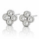 A pair of diamond stud earrings in a four-petal flower setting, crafted in silver-toned metal with a central pearl-like bead, shown on a reflective white surface.