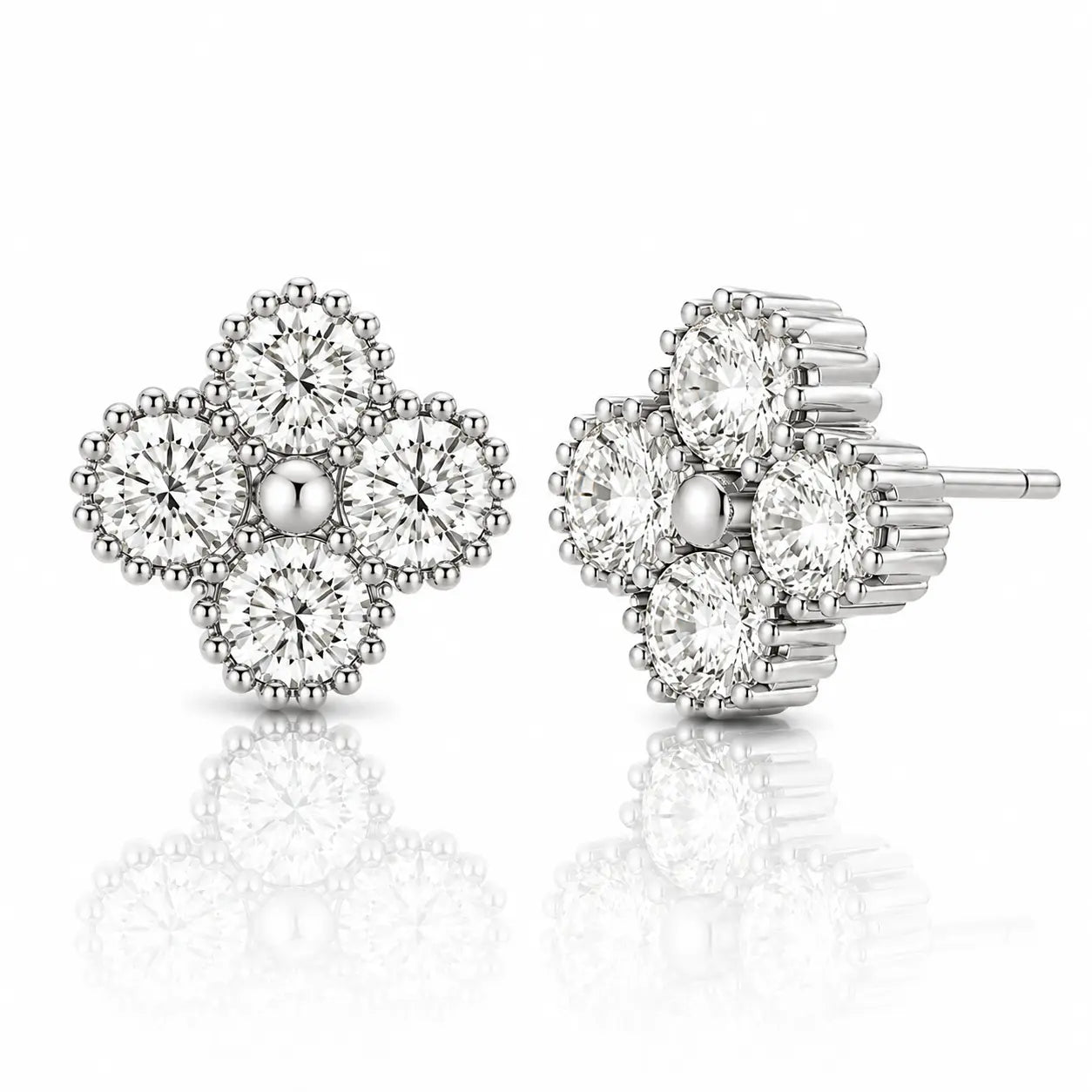 A pair of silver-toned stud earrings with a floral clover design, featuring clear round-cut gemstones in a prong setting. One earring is shown from the front and the other from the side/back, set against a clean white background with a soft reflection below.