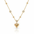A gold necklace featuring a polished heart-shaped pendant and several small bezel-set clear stones along the chain, displayed on a clean white background with a soft reflection.