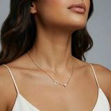 Woman wearing a delicate necklace with a heart pendant and pearl on a neutral background