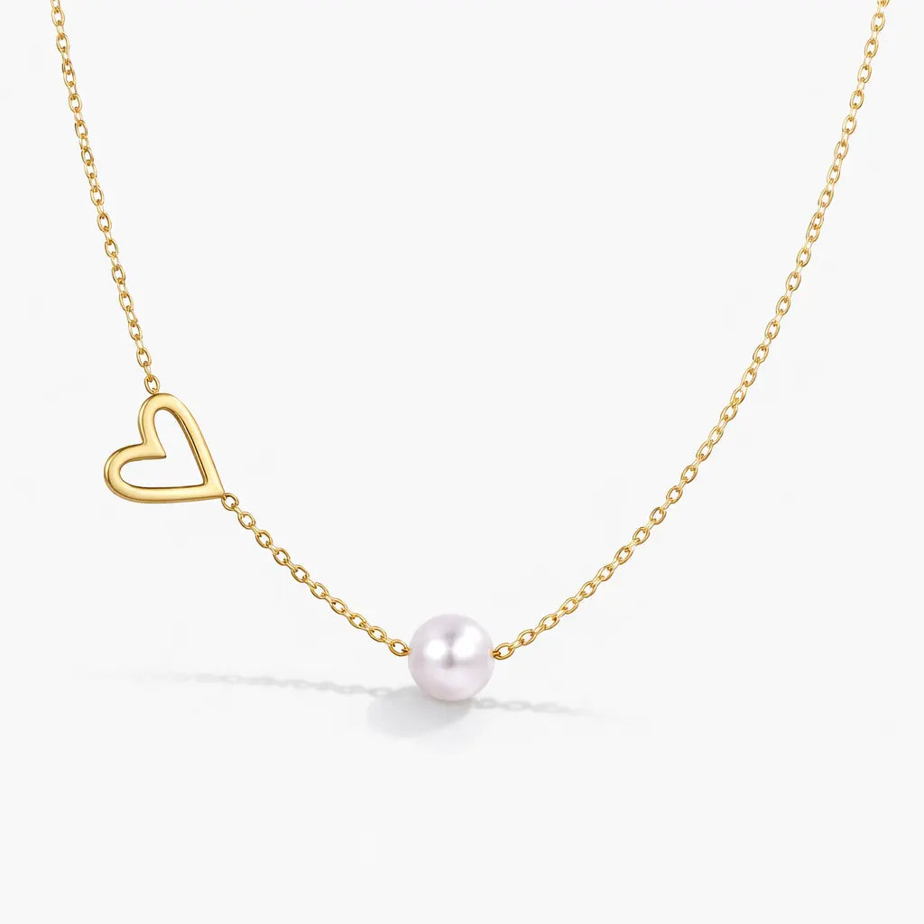 Gold necklace with a heart pendant and pearl on a white background