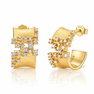 A pair of gold huggie hoop earrings with clear gemstones, shown from both the front and side angles on a white reflective background. The gold is marked with '14K' and 'S925'.