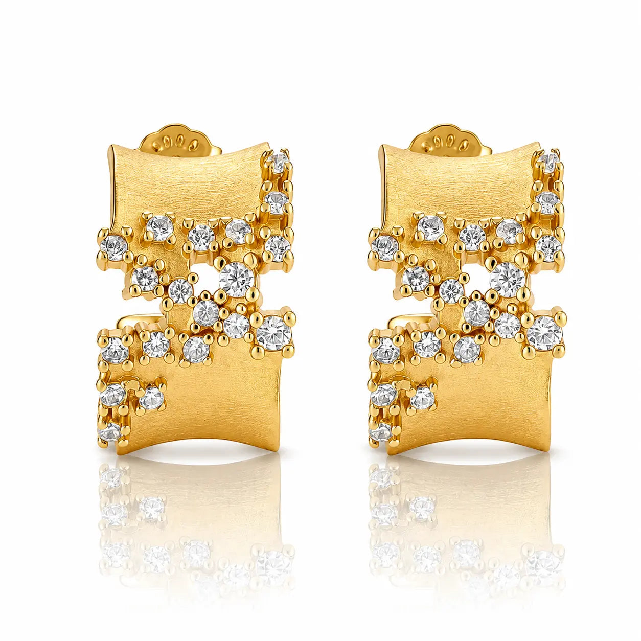A pair of gold geometric stud earrings with clear gemstones, displayed on a clean white background with a soft reflection below.