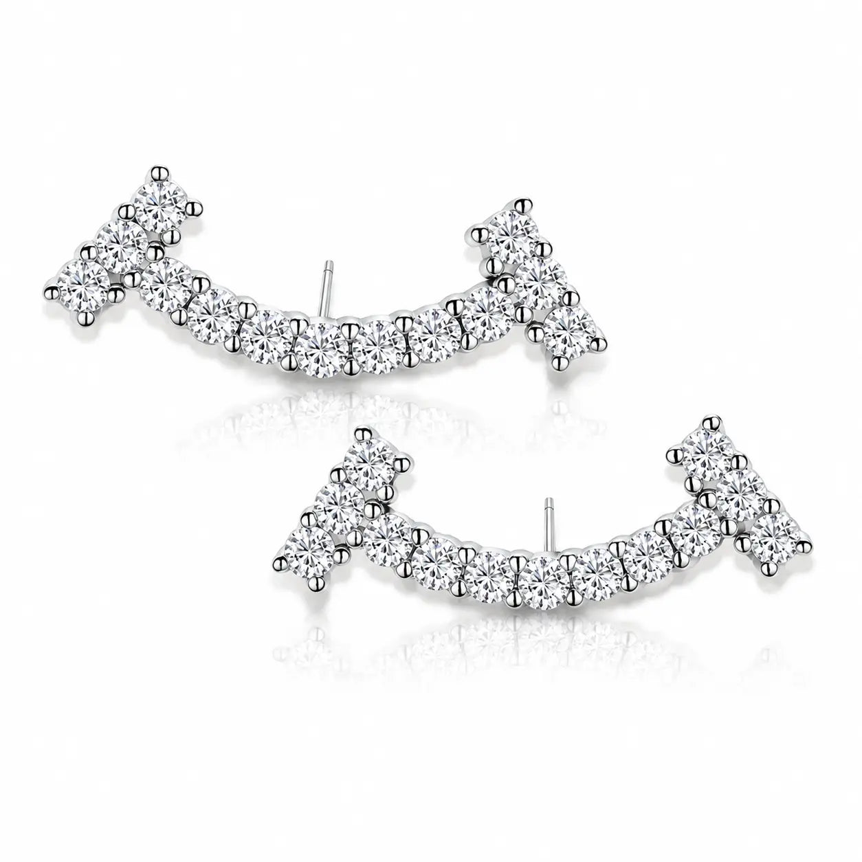 A pair of silver-toned crescent-shaped stud earrings set with clear pavé gemstones, displayed on a clean white background with a soft reflection.