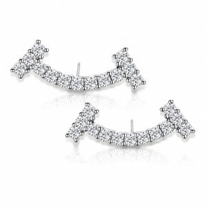 A pair of silver-toned crescent-shaped stud earrings set with clear pavé gemstones, displayed on a clean white background with a soft reflection.