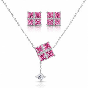 Silver-tone jewelry set featuring a necklace, matching stud earrings, and a small pendant charm. The necklace and earrings have square pink gemstone centers set with clear stones in a cross pattern, with the necklace chain extending to the edges of the frame.