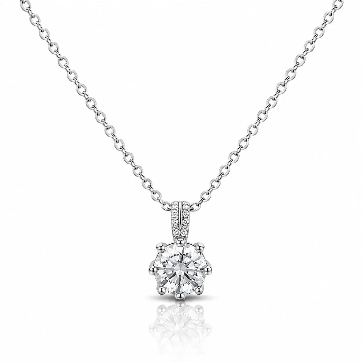 A silver solitaire necklace with a round-cut diamond pendant and a pavé diamond bail, displayed on a clean white background with a soft reflection below.