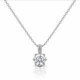 A silver solitaire necklace with a round-cut diamond pendant and a pavé diamond bail, displayed on a clean white background with a soft reflection below.