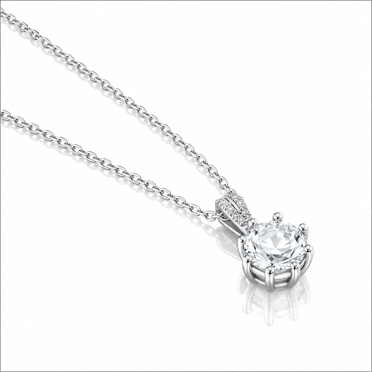 A silver-toned necklace with a round-cut diamond pendant in a prong setting, shown on a clean white background with a soft reflection.