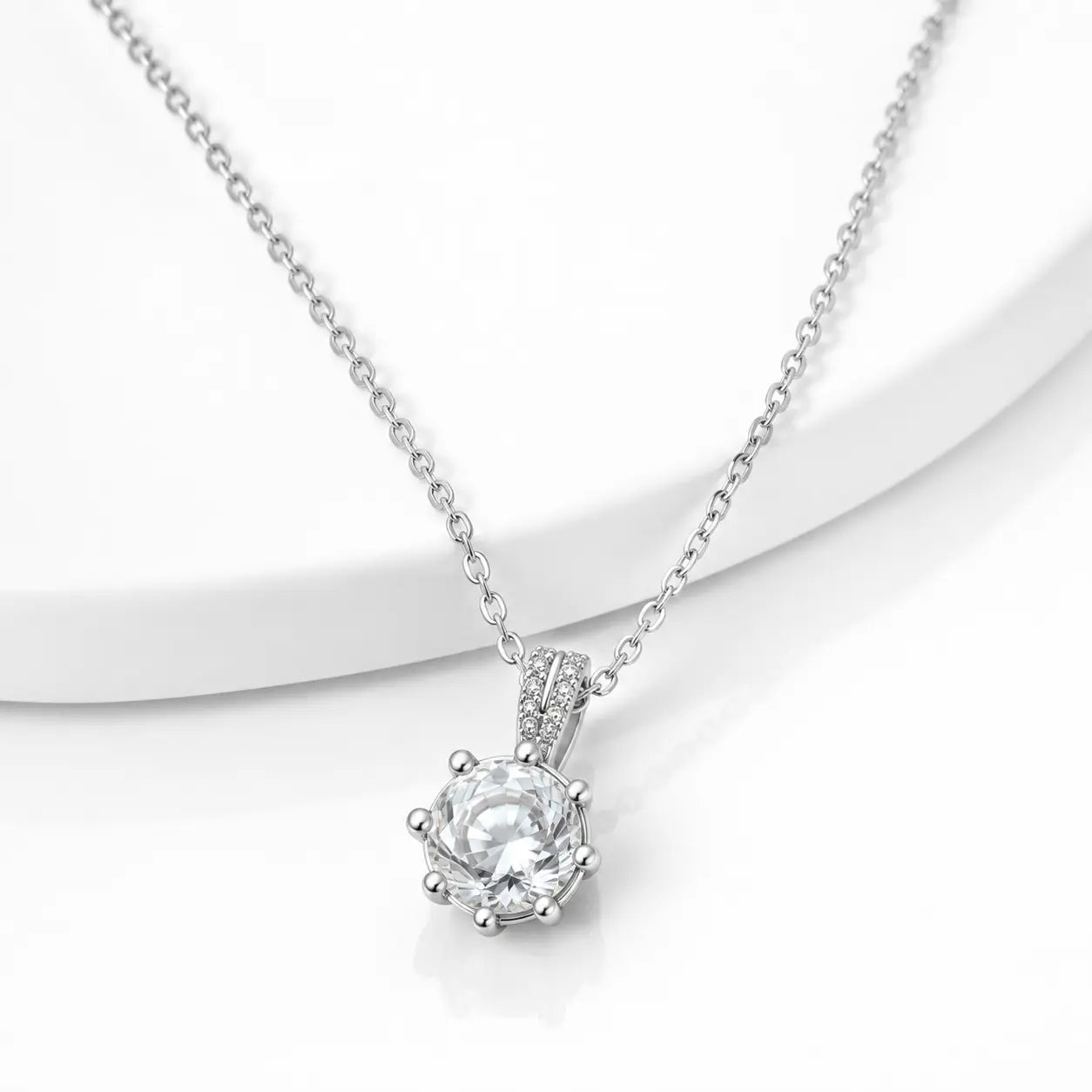 A silver-toned necklace with a delicate cable chain and a heart-shaped bezel-set clear gemstone pendant, displayed on a clean white background.