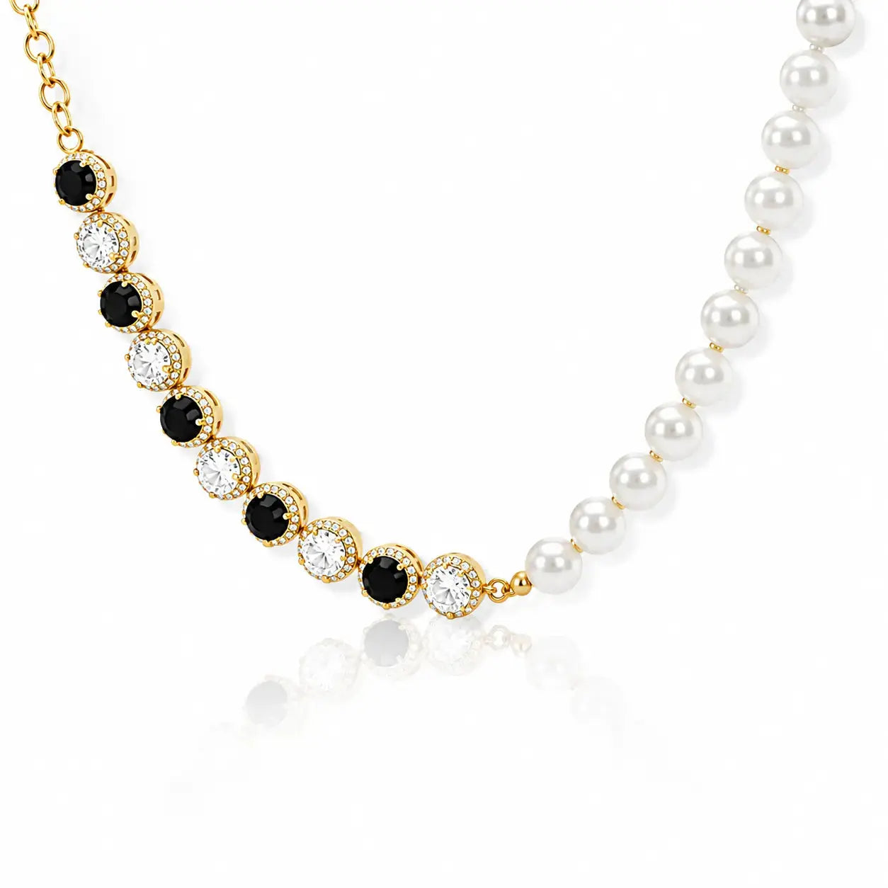 A gold and pearl necklace featuring alternating rows of black and clear round stones in gold bezel settings, with one row transitioning into a strand of white pearls on a white background.