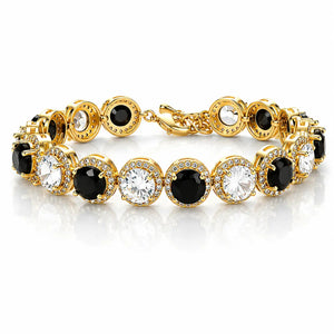A gold tennis bracelet featuring alternating round black and clear gemstones, each surrounded by a halo of small clear crystals, set against a clean white background with a soft reflection.