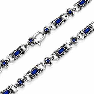 Silver-toned chain bracelet with rectangular blue gemstones and ornate filigree diamond-shaped links, shown on a white background.