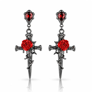 A pair of gothic dangle earrings featuring dark silver-toned metal crosses with red rose details and red gemstone accents, shown on a clean white background with subtle reflections.